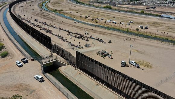 Migrantes esperando a lo largo del muro fronterizo tras cruzar el Río Bravo en la frontera entre Estados Unidos y México en El Paso. , Texas, el 11 de mayo de 2023. (Foto de Patrick T. Fallon / AFP)