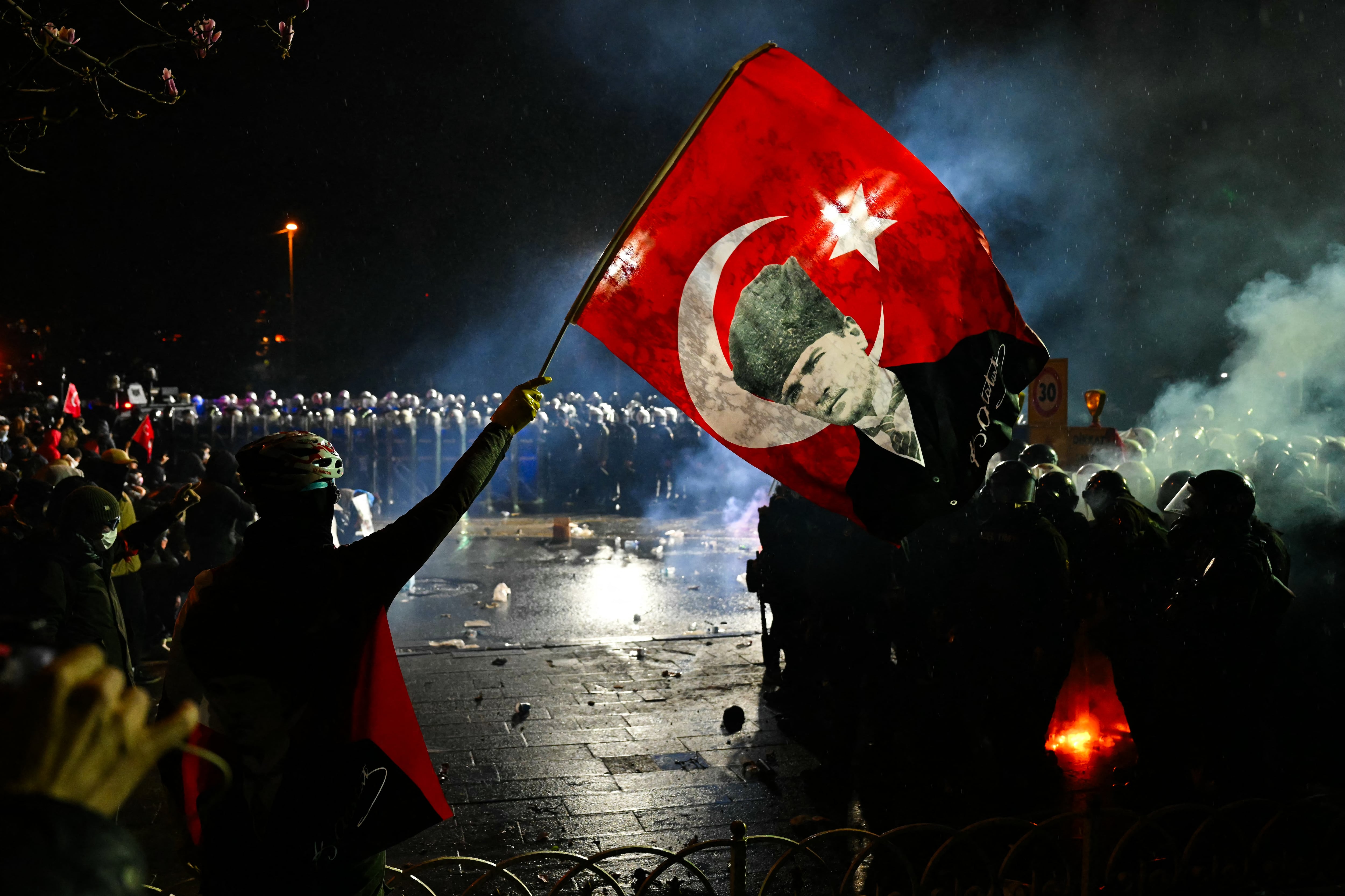 Un manifestante sostiene una bandera con Mustafa Kemal Atatürk, padre fundador del Estado moderno turco, durante enfrentamientos con la policía antidisturbios. (Foto de YASIN AKGUL / AFP).