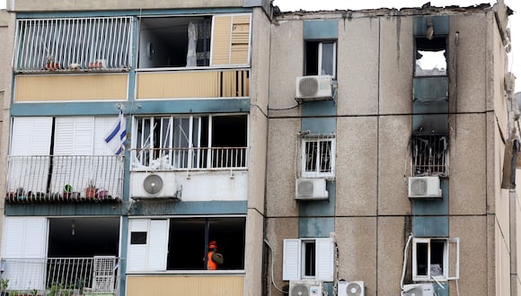 Un trabajador de emergencia israelí se para junto a la ventana mientras observa los daños sufridos por un edificio parcialmente destruido tras un ataque con cohetes desde la Franja de Gaza palestina, en la ciudad israelí de Tel Aviv el 27 de octubre de 2023, en medio de las batallas en curso entre Israel y los palestinos. (Foto de JACK GUEZ / AFP)