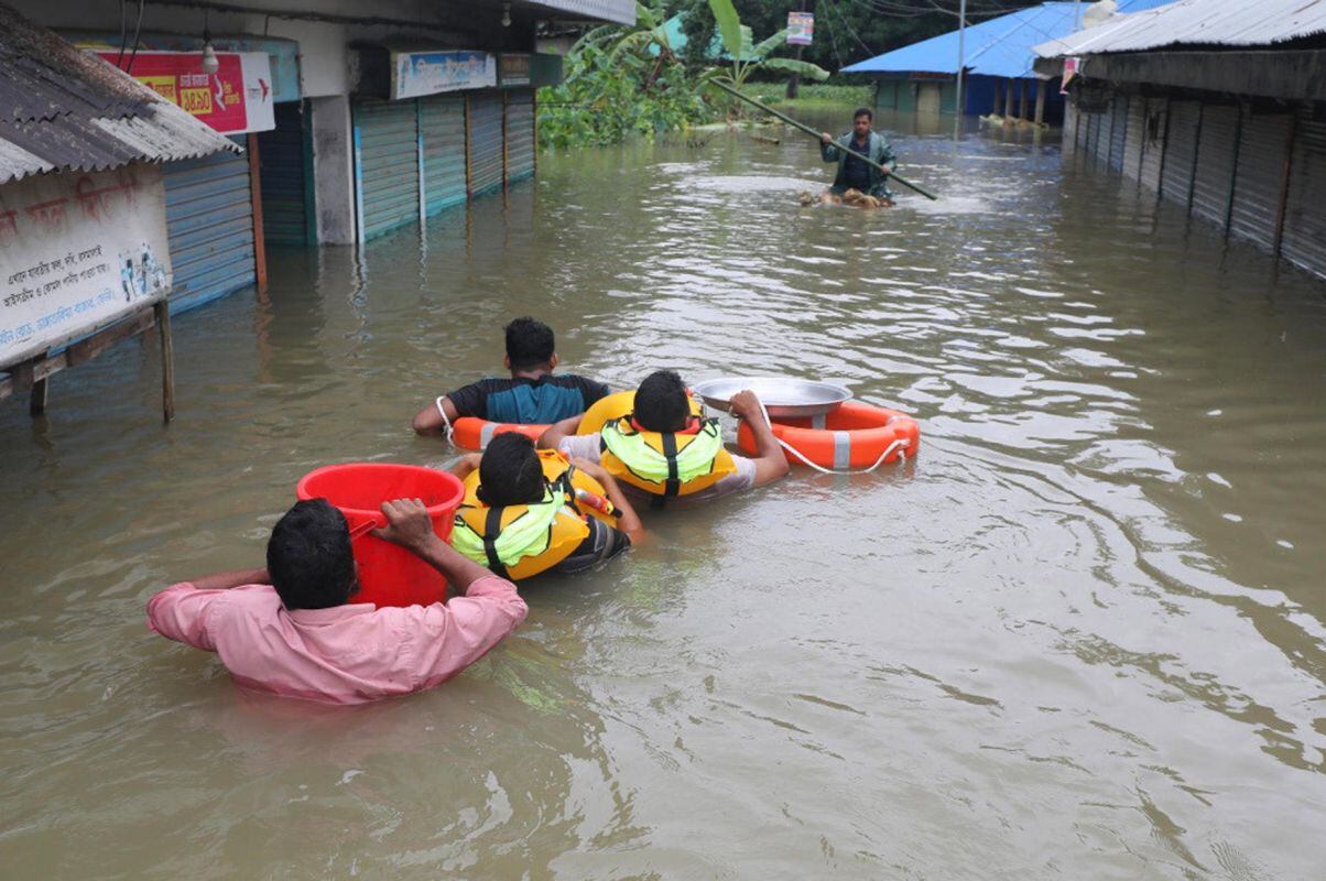 Varias personas intentan desplazarse en una calle inundada este jueves en Feni, Bangladés. Según fuentes gubernamentales, al menos dos personas han muerto en todo el país por cause de estas inundaciones. Foto: EFE/STR