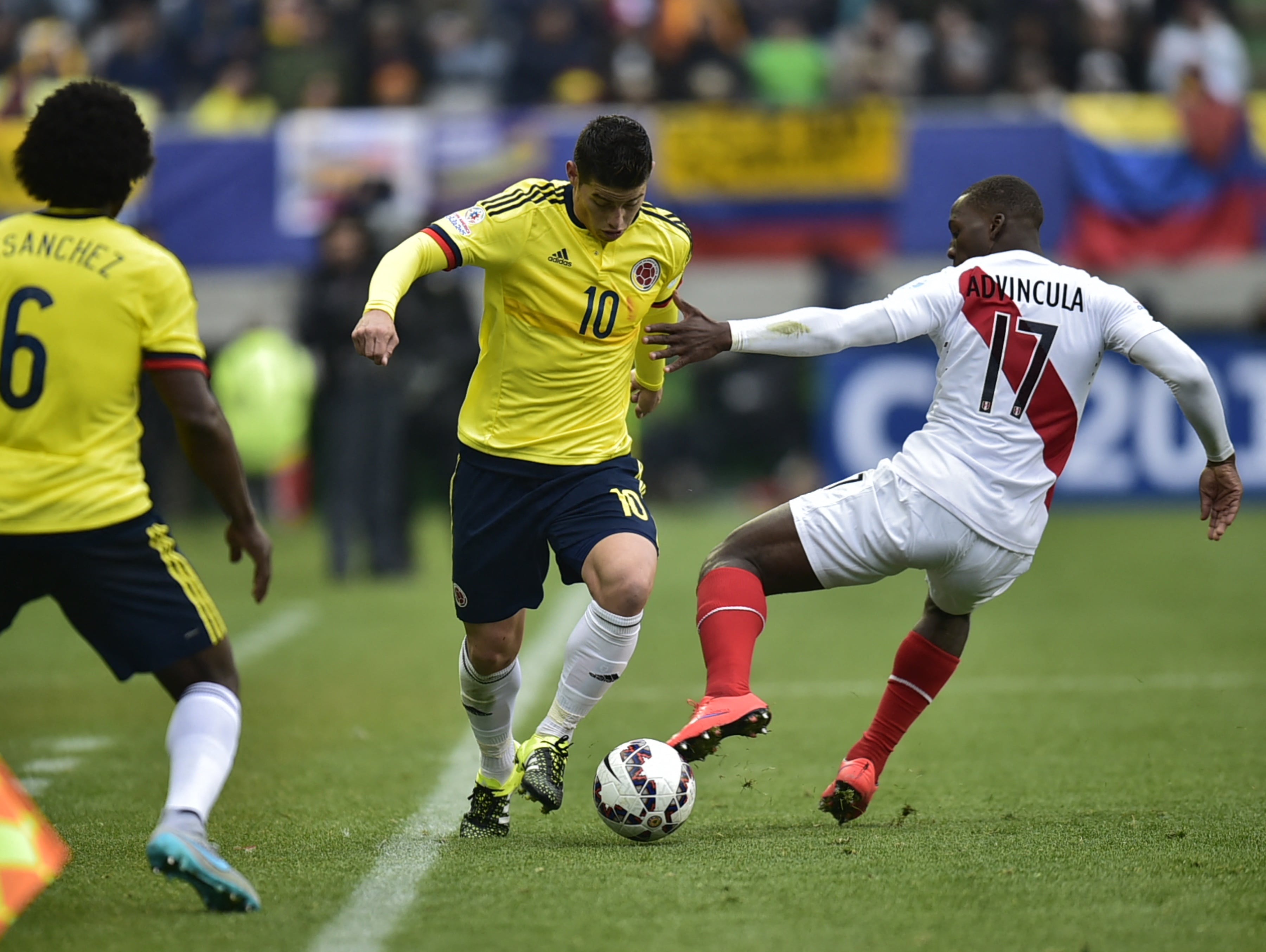 Colombia's midfielder James Rodriguez (C) os marked by Peru's defender Luis Advincula during their 2015 Copa America football championship match, in Temuco, Chile, on June 21, 2015. AFP PHOTO / RODRIGO BUENDIA (Photo by RODRIGO BUENDIA / AFP)