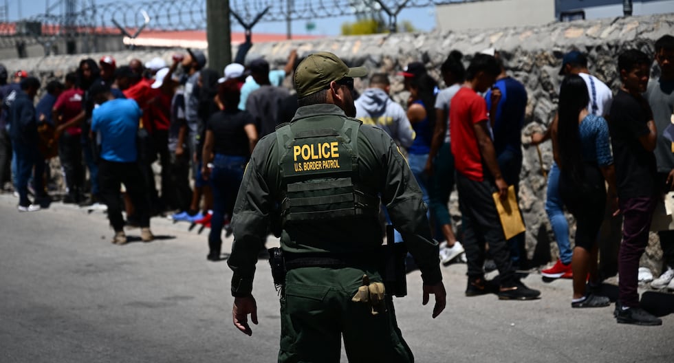 Un agente de la Patrulla Fronteriza de Estados Unidos camina junto a una fila de migrantes que esperan entregarse a los agentes para su procesamiento cerca del puerto de entrada Paso del Norte, el 9 de mayo. 2023. (Foto de Patrick T. Fallon / AFP).