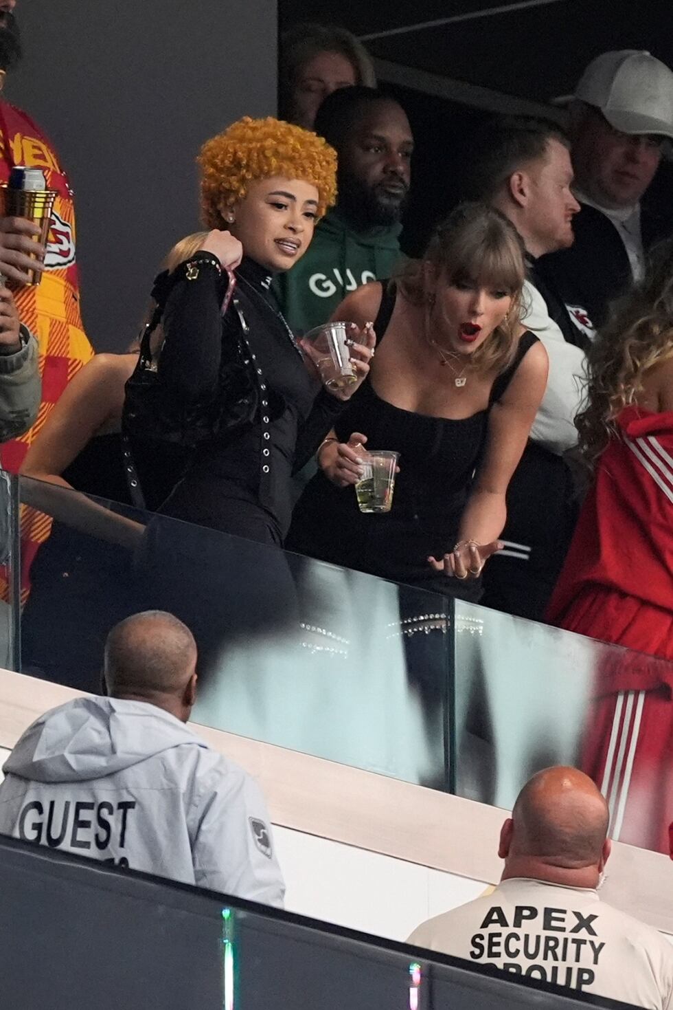 Ice Spice junto a Taylor Swift, quien intercambia palabras con miembros de seguridad.