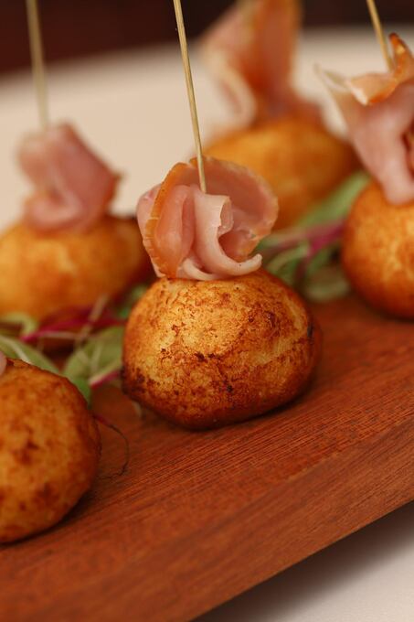 Unas bolitas de yuca rellenas de queso coronadas con jamón serrano.