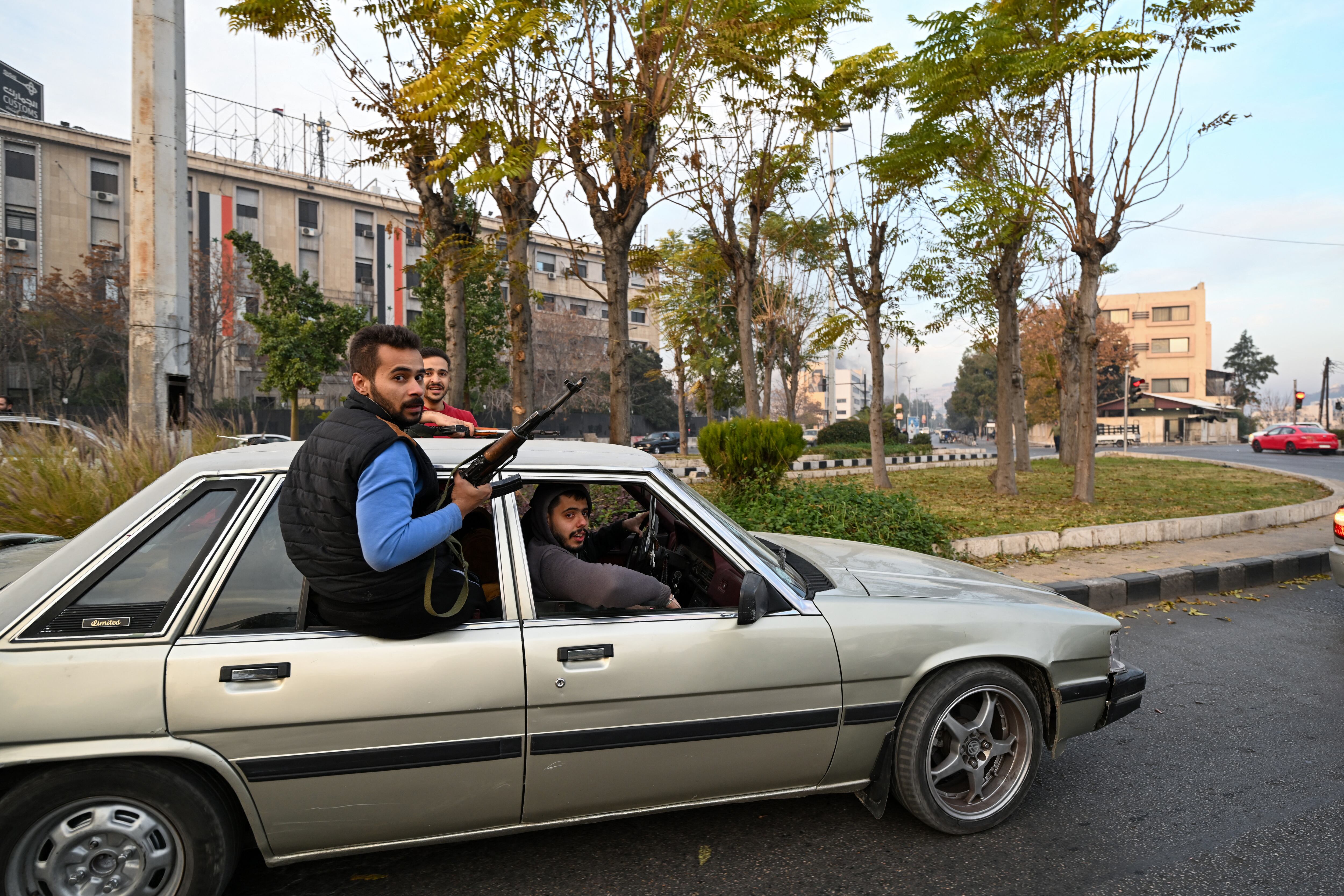La gente vitorea mientras conduce por una calle de Damasco el 8 de diciembre de 2024. Los rebeldes liderados por islamistas declararon que habían tomado Damasco en una ofensiva relámpago, lo que hizo huir al presidente Bashar al-Assad y puso fin a cinco décadas de gobierno del Baaz en Siria. Foto: LOUAI BESHARA / AFP