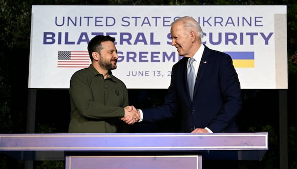 El presidente estadounidense Joe Biden y el presidente ucraniano Volodymyr Zelensky se dan la mano después de firmar un acuerdo de seguridad bilateral el 13 de junio de 2024. (MANDEL NGAN / AFP).