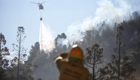 Esta imagen publicada por Parques Nacionales de Argentina a través de Télam muestra un helicóptero arrojando agua para apagar un incendio forestal en el Parque Nacional Los Alerces en la provincia de Chubut, Argentina, el 26 de enero de 2024. (Foto por Folleto / Parques Nacionales de Argentina / AFP)