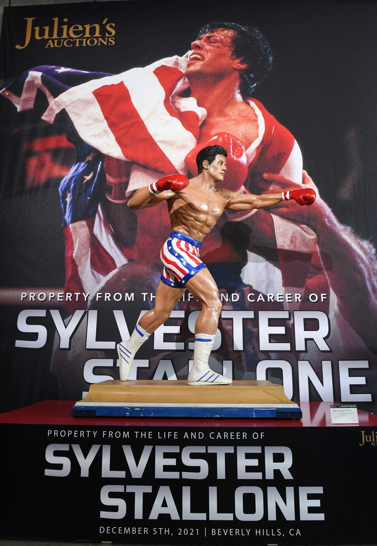 Una estatua de tamaño natural de Sylvester Stallone como Rocky Balboa se exhibe frente a una impresión de edición limitada del póster de Rocky 4 firmado por Sylvester Stallone y Stephen Holland (Foto: Valerie Macon / AFP)