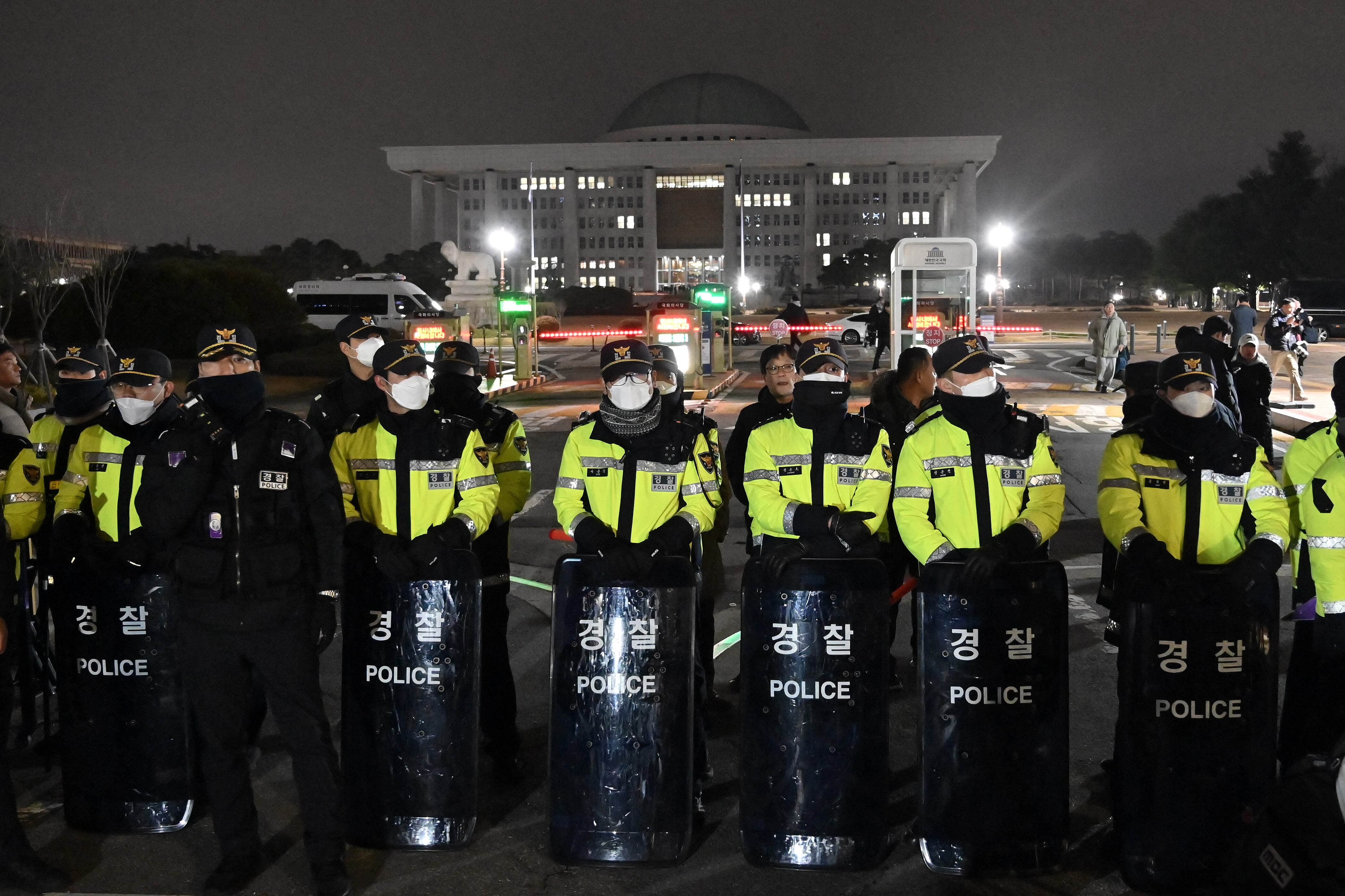 La policía hace guardia frente a la puerta principal de la Asamblea Nacional en Seúl el 3 de diciembre de 2024, después de que el presidente de Corea del Sur, Yoon Suk Yeol, declarara la ley marcial de emergencia. (Foto de Jung Yeon-je / AFP).