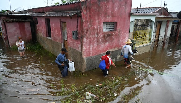 La gente camina por una calle inundada en Batabano, provincia de Mayabeque, Cuba. (Foto de Yamil LAGE / AFP)