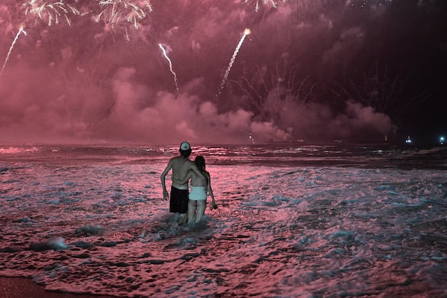 Dos personas observan los tradicionales fuegos artificiales de Año Nuevo desde las aguas de la playa de Copacabana en Río de Janeiro, Brasil, la madrugada del 1 de enero de 2026. (Foto de TERCIO TEIXEIRA / AFP).