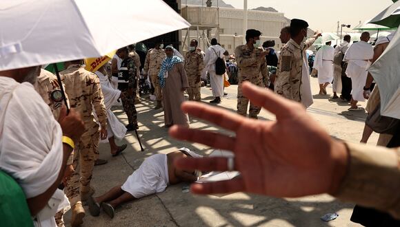 Un miembro de las fuerzas de seguridad sauditas impide que la gente se acerque mientras un hombre afectado por el calor abrasador yace en el suelo durante la llegada de peregrinos musulmanes que llegan para realizar el ritual simbólico de 'lapidación del diablo' como parte de la peregrinación hajj. (Foto de Fadel Senna / AFP)