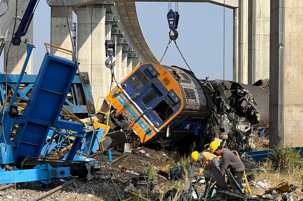 Trabajadores registran los restos de un tren de pasajeros tras el derrumbe de una grúa de construcción sobre él en el distrito de Sikhio, Nakhon Ratchasima, Tailandia, el 14 de enero de 2026. Foto: EFE/EPA/NARONG SANGNAK