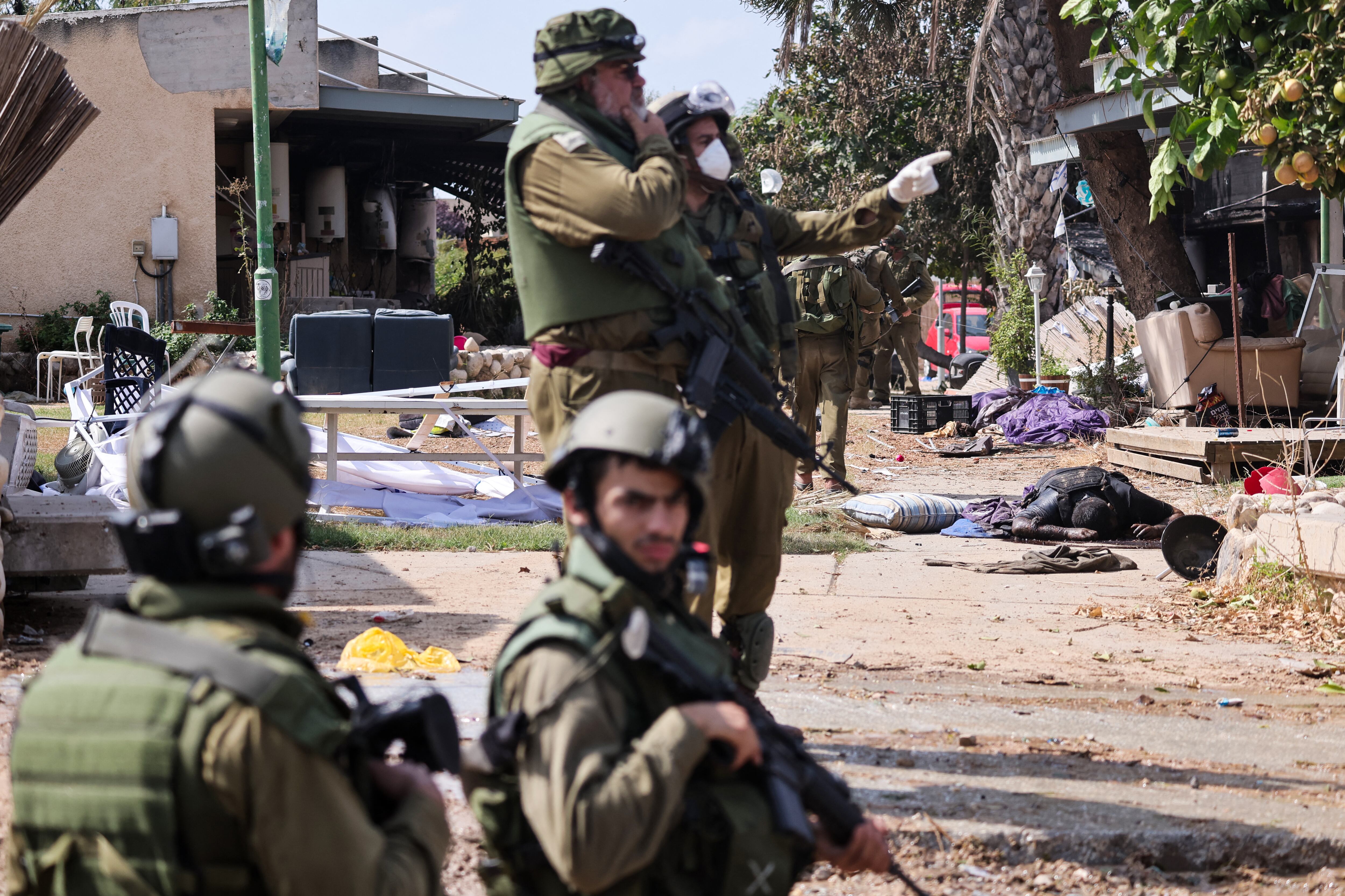 Soldados de Israel se encuentran cerca del cuerpo de un militante palestino en Kfar Aza, en la frontera con la Franja de Gaza, el 10 de octubre de 2023. (Foto de Thomas COEX / AFP).