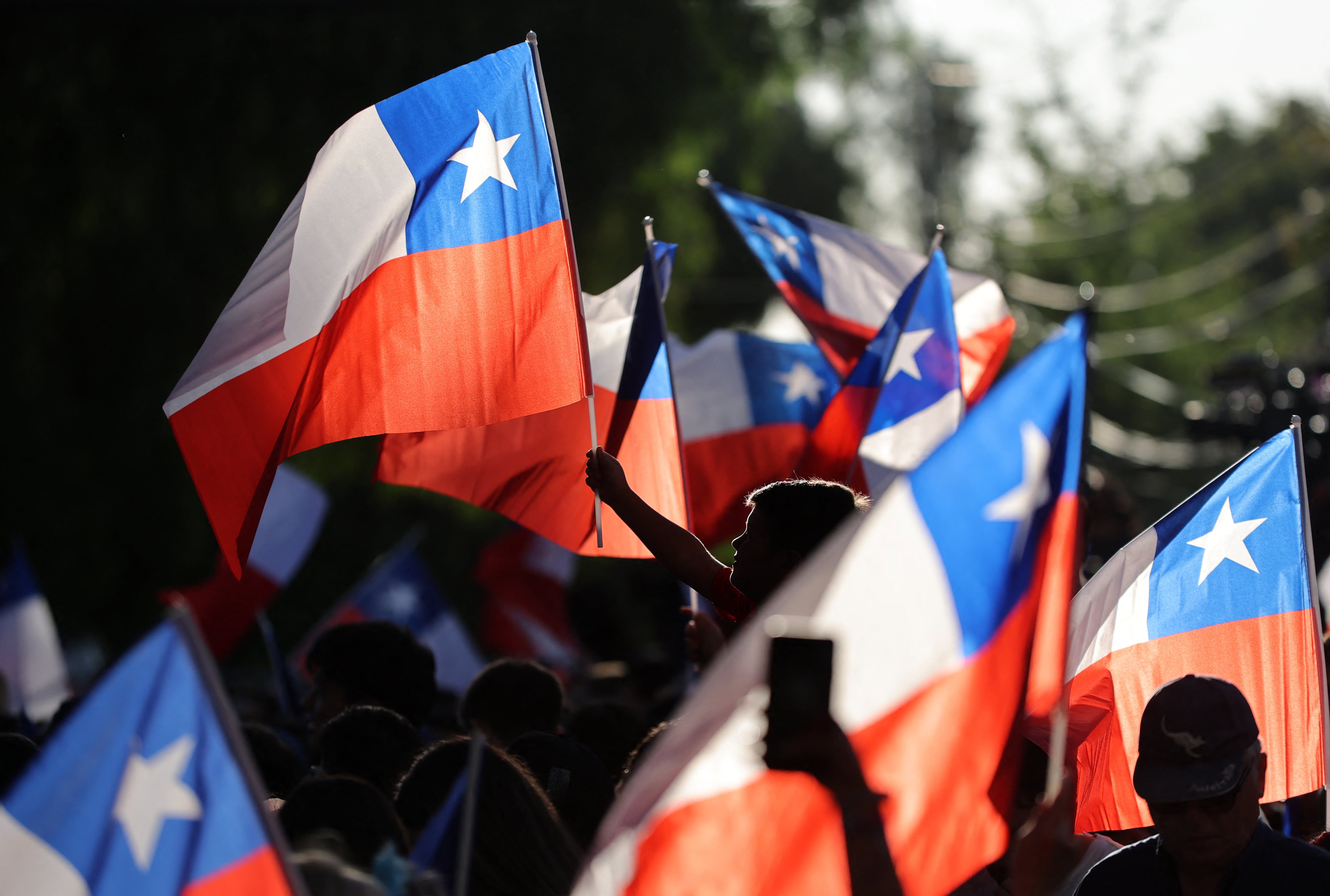 Partidarios del candidato presidencial chileno José Antonio Kast ondean banderas nacionales tras los primeros resultados de la segunda vuelta de las elecciones presidenciales. (Foto de Javier TORRES / AFP).