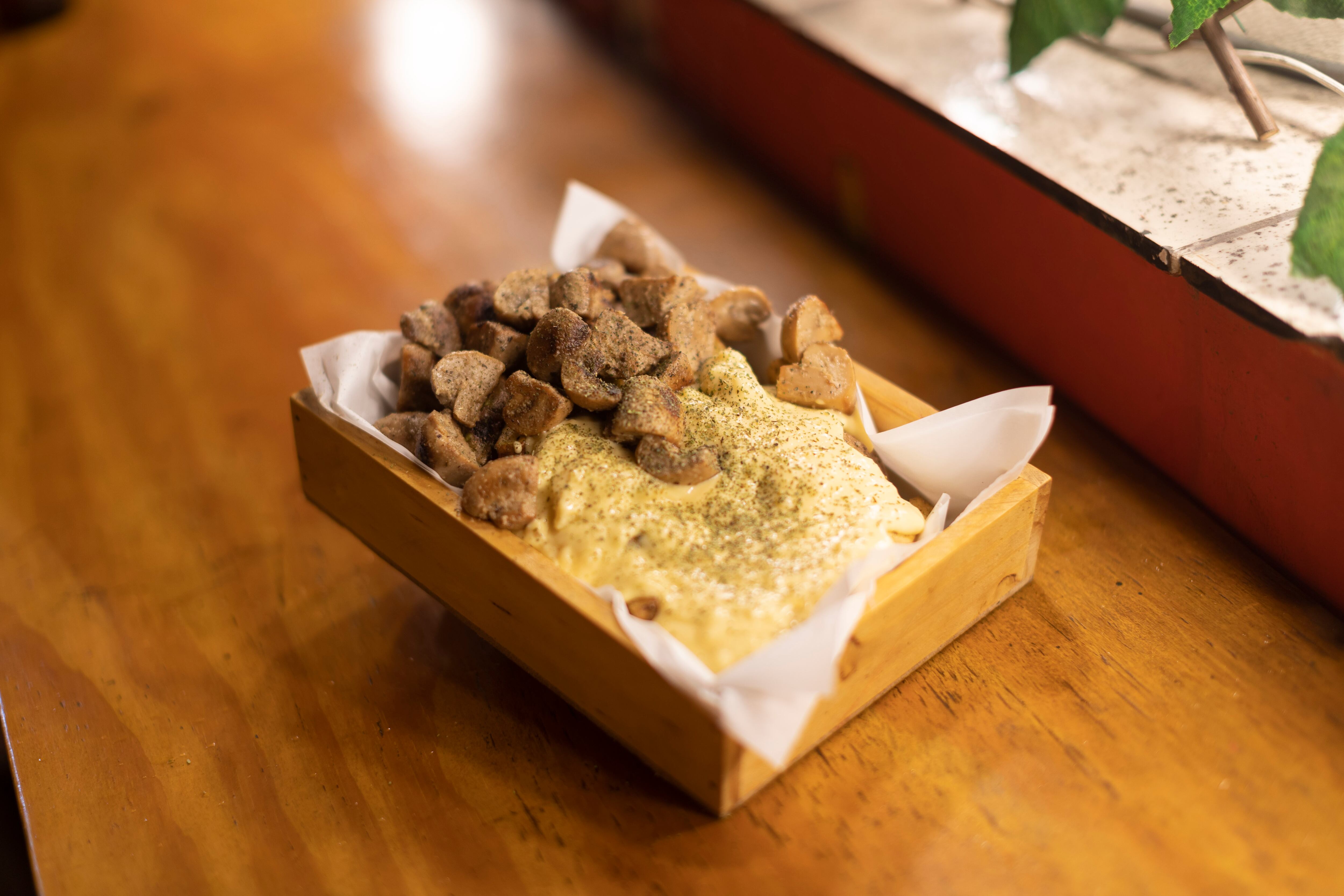 Combinación de champiñones al ajillo y chimichurri con papas fritas y salsa de queso.