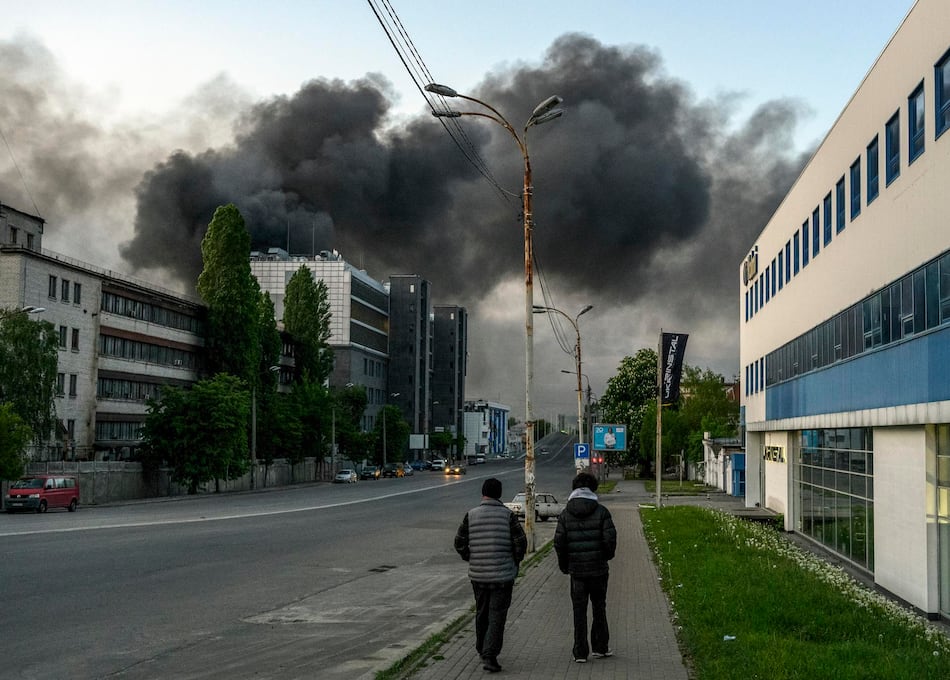 Residentes locales caminan por una acera mientras el humo se eleva sobre una calle tras un ataque ruso contra Kiev, Ucrania, el 14 de mayo de 2026. (EFE/EPA/MAXYM MARUSENKO).