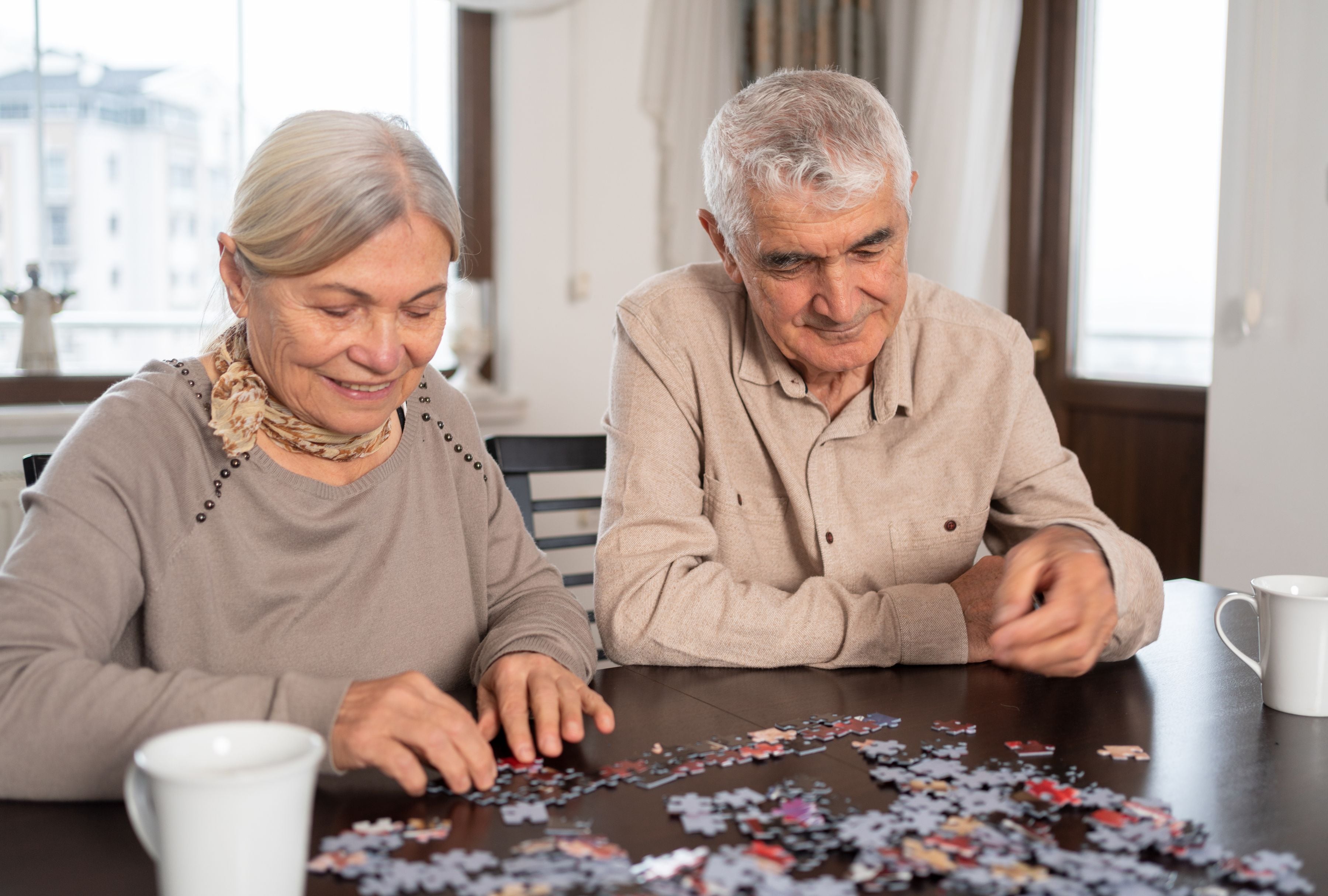 Una pareja de adultos mayores intenta completar un rompecabezas. (Foto: aquaArts studio/iStock)