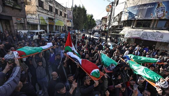 Dolientes cargan los cuerpos envueltos en banderas de los palestinos asesinados durante un ataque israelí en Jenin, en la Cisjordania ocupada, durante su funeral el 7 de enero de 2024. (Foto de Zain JAAFAR / AFP)