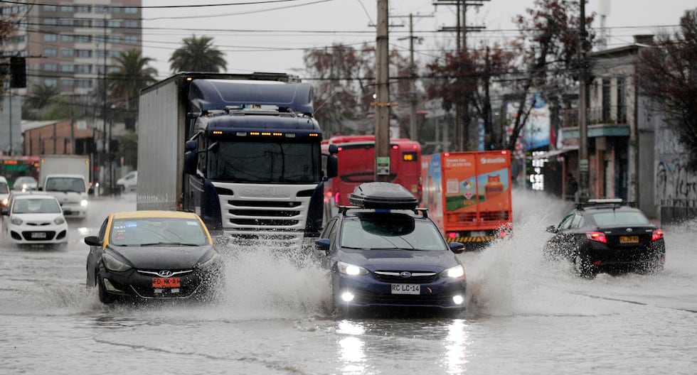 Vehículos transitan por calles inundadas causadas por la lluvia este jueves en Santiago de Chile. (EFE/Elvis González).