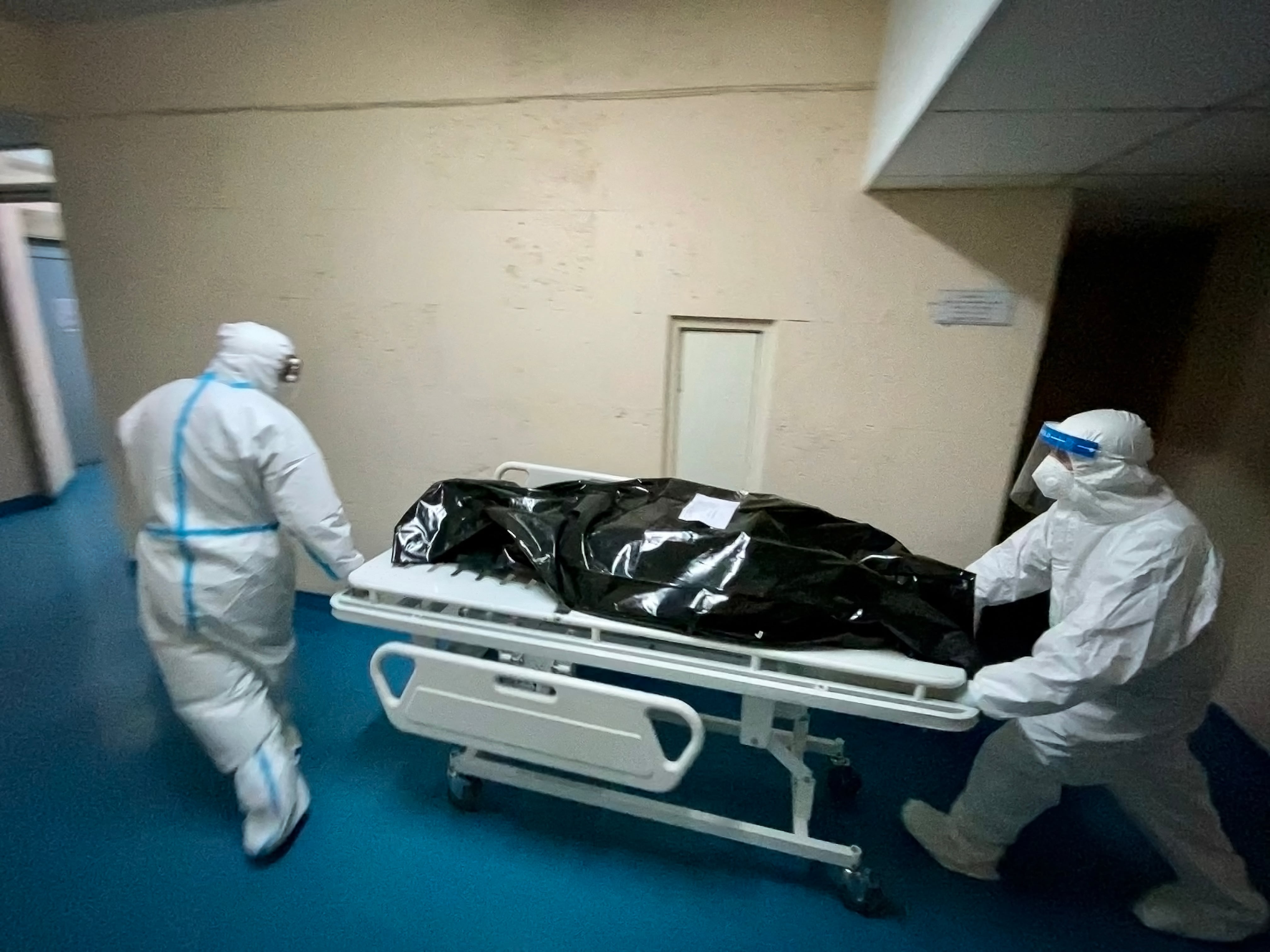 Dos hombres con trajes de protección transportan el cadáver de un paciente con COVID-19 a la morgue en Chisinau, la capital de Moldavia, el 24 de marzo de 2021. (Daniel MIHAILESCU / AFP).