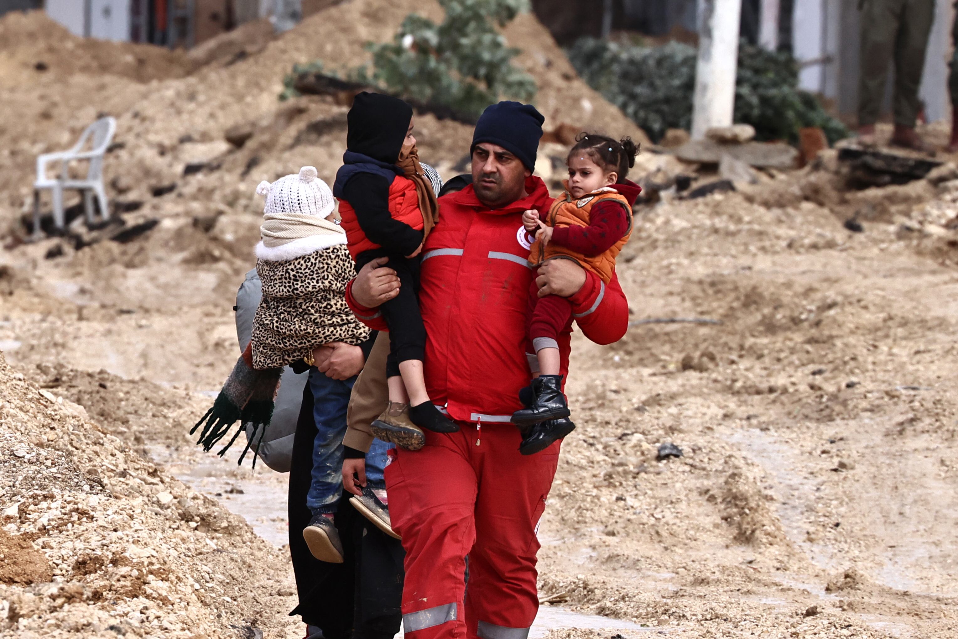 Un miembro de la Media Luna Roja ayuda a los palestinos a abandonar sus hogares durante una redada del ejército israelí en el campo de refugiados de Nur Shams, cerca de Tulkarem, en la Cisjordania ocupada, el 10 de febrero de 2025. (Foto de Zain JAAFAR / AFP).