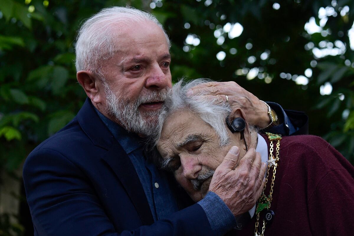 El presidente de Brasil, Luiz Inácio Lula da Silva, abraza al expresidente uruguayo José Mujica después de condecorarlo con la Orden Nacional de la Cruz del Sur, en Montevideo, el 5 de diciembre de 2024. (Foto de Dante Fernandez / AFP)