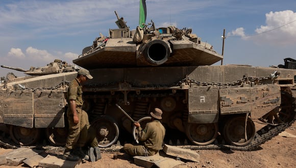 Soldados israelíes trabajan en sus tanques en un campamento militar cerca de la frontera de Israel con la Franja de Gaza el 8 de abril de 2024. (Foto de Menahem Kahana / AFP).