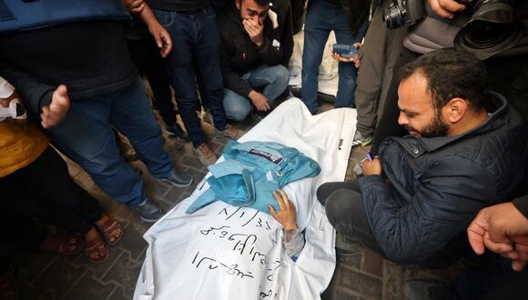 Compañeros periodistas lloran ante el cuerpo de Hamza Wael Dahdouh, periodista de la cadena de televisión Al Jazeera, que murió en un ataque aéreo israelí durante su funeral en Rafah, en la Franja de Gaza, el 7 de enero de 2024. (Foto de AFP)