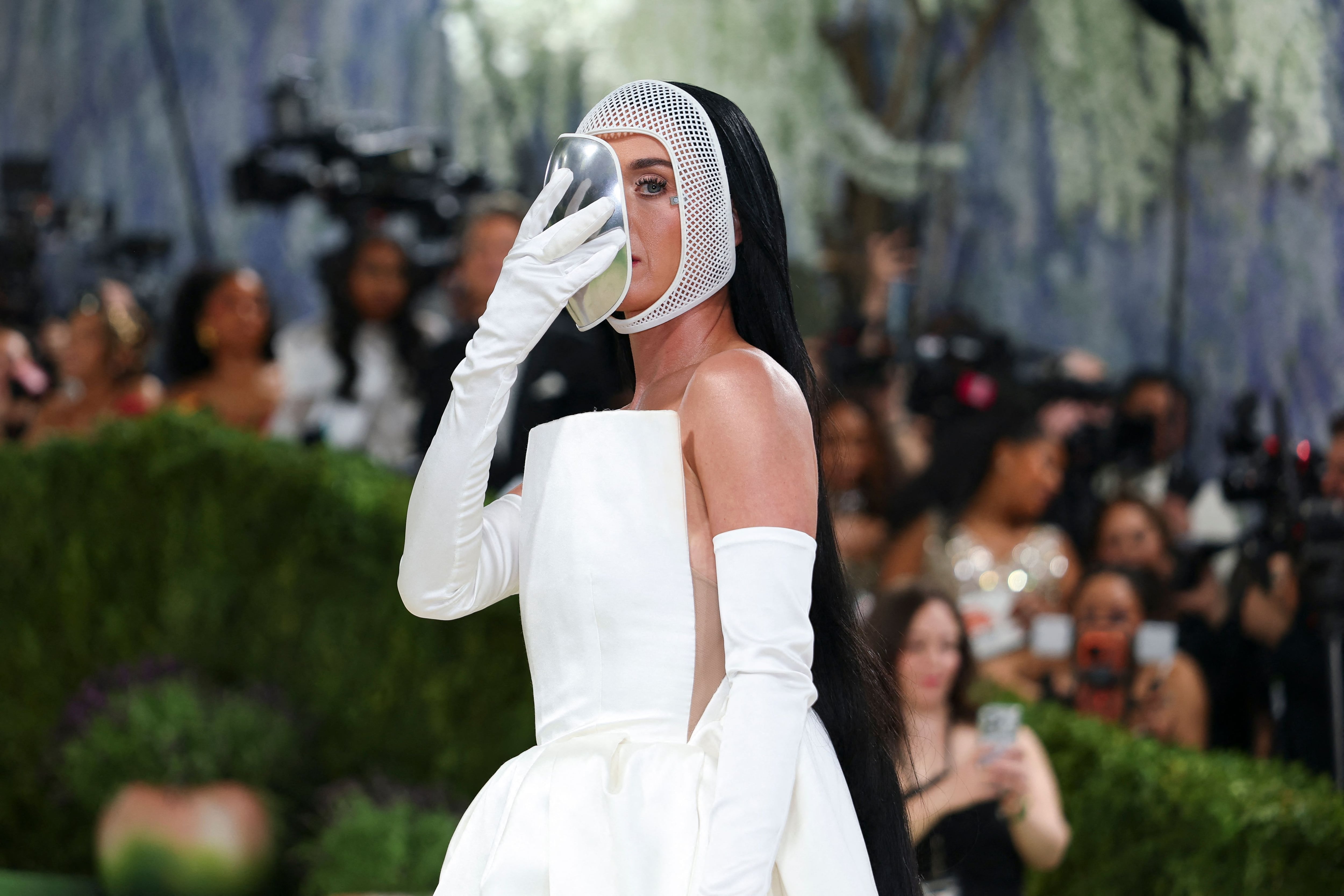 La cantante de Firework , Katy Perry, aparece en la Met Gala 2026 con un vestido strapless blanco de Stella McCartney, acompañado de guantes de ópera y una máscara facial plateada de efecto espejo.