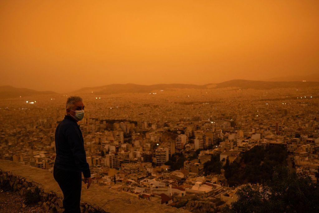 Un hombre con una mascarilla mira hacia la ciudad de Atenas desde la colina Tourkovounia. (GETTY IMAGES).
