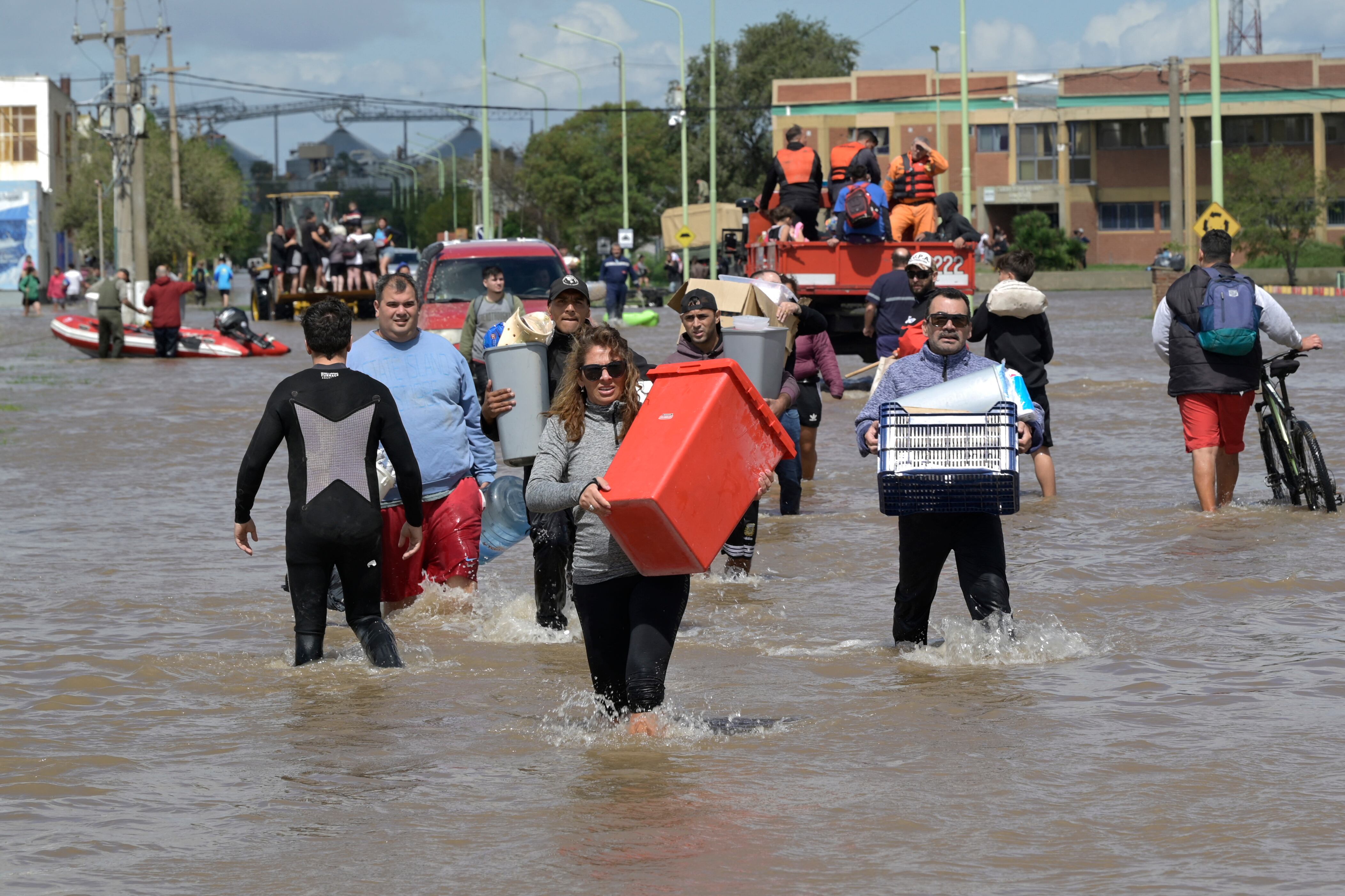 Personas con pertenencias caminan por las aguas inundadas un día después de una fuerte tormenta en Bahía Blanca, a 600 km al sur de Buenos Aires, el 8 de marzo de 2025. Foto: PABLO PRESTI / AFP