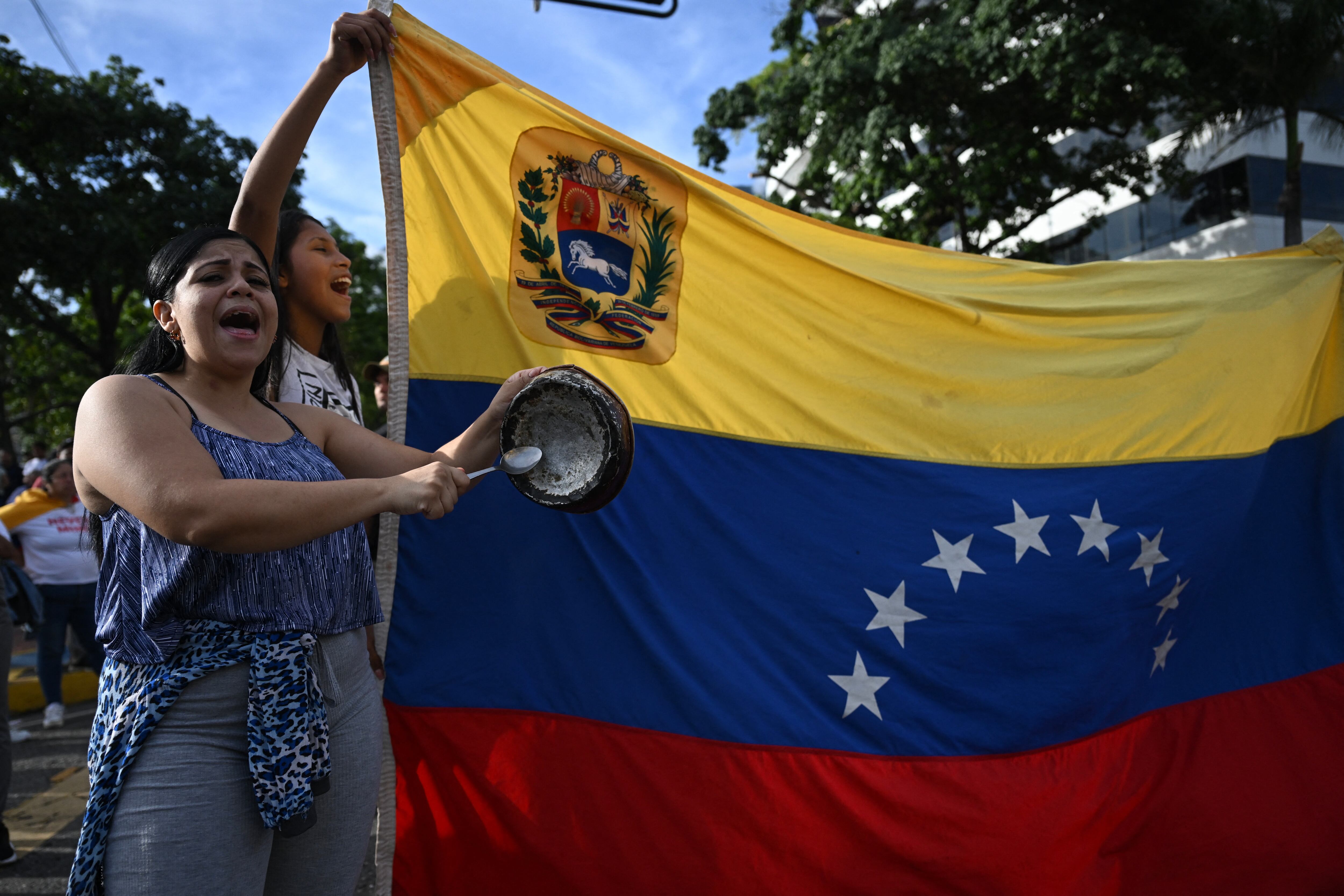 Una manifestante golpea una sartén junto a una bandera de Venezuela durante una protesta contra el gobierno del presidente Nicolás Maduro en Caracas el 29 de julio de 2024. (Foto de Raúl ARBOLEDA / AFP).