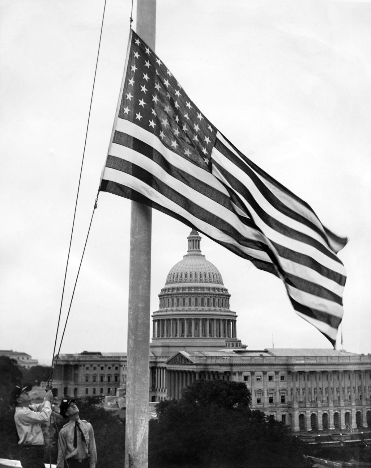 No muy lejos del Capitolio (al fondo), la policía del Senado bajó la bandera a media asta en lo alto del edificio de la Oficina del Senado, tras la repentina muerte del demócrata Joe T.Robinson (Joseph Taylor Robinson), el gobernador 23 de Arkansas y líder de la mayoría de el Senado de los Estados Unidos el 14 de julio de 1937 en Washington. (Foto: ACME / AFP)