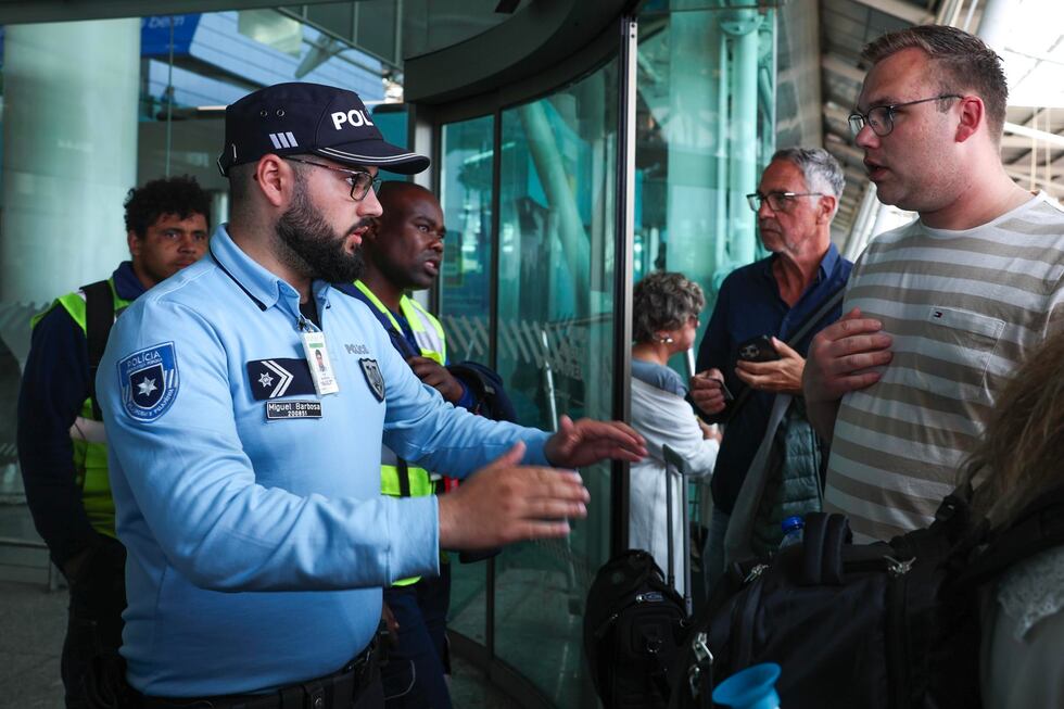 Un policía atiende a los pasajeros explicando que el Aeropuerto Humberto Delgado de Lisboa está cerrado en la zona de llegadas debido al apagón que afecta a España y Portugal. EFE/EPA/TIAGO PETINGA
