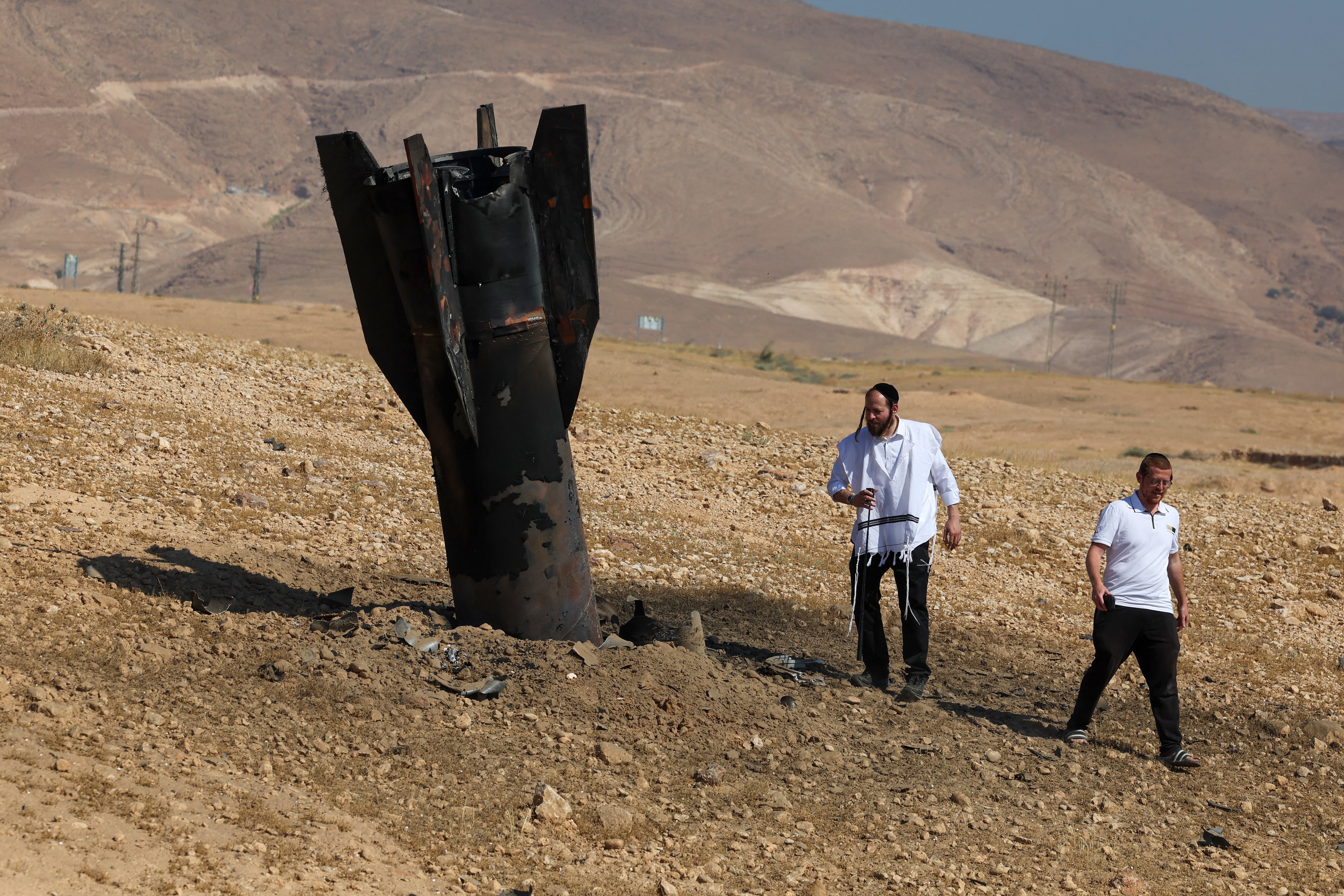Dos hombres examinan un misil caído en las afueras de Jericó el 8 de junio de 2026, tras los ataques de Irán y de los rebeldes hutíes contra Israel. (Foto de Ahmad GHARABLI / AFP).
