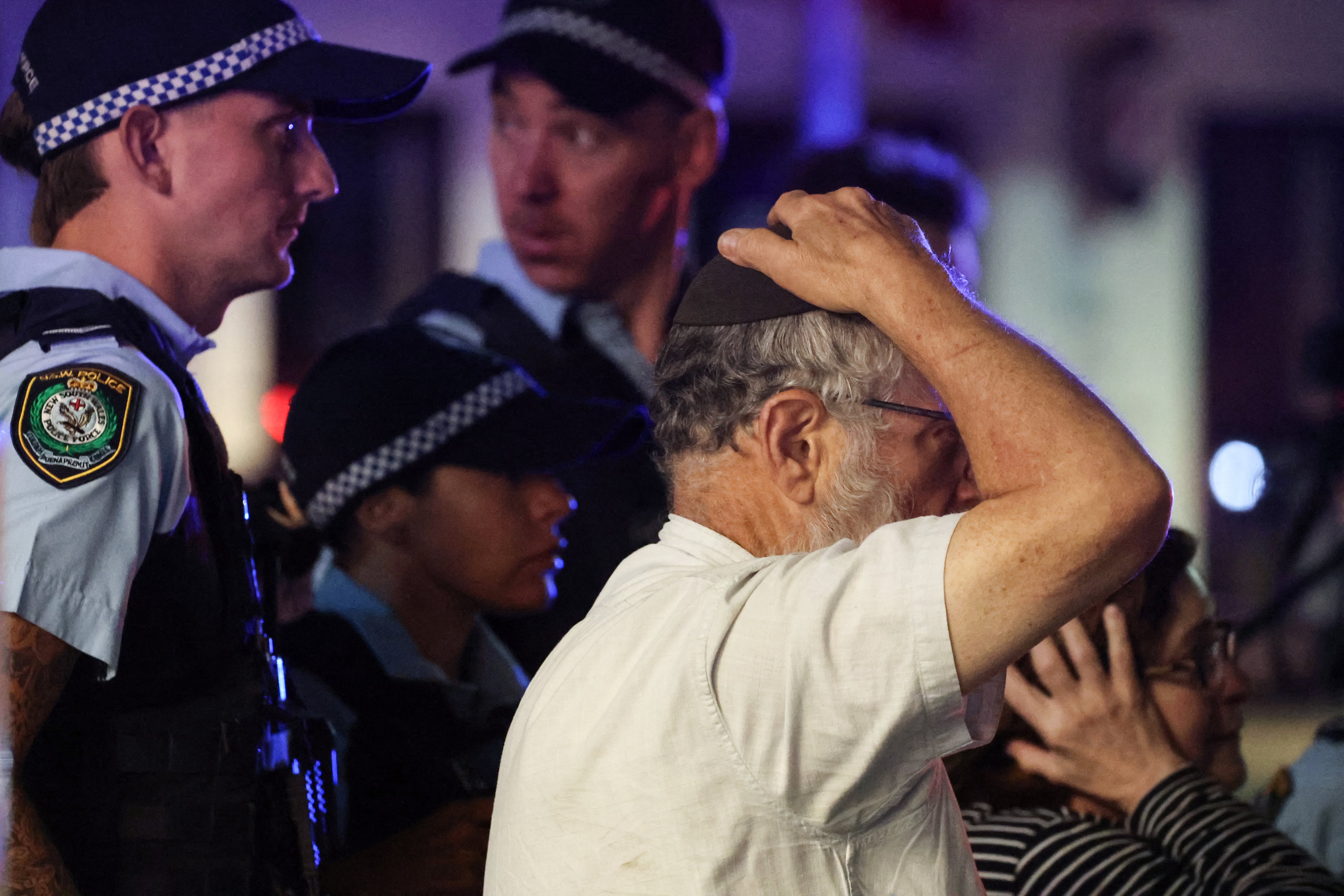 Un miembro de la comunidad judía reacciona mientras camina con la policía hacia el lugar de un tiroteo en Bondi Beach, Sídney, el 14 de diciembre de 2025. (Foto de DAVID GRAY / AFP).