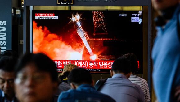 Gente se sienta cerca de un televisor que muestra imágenes de archivo durante un reportaje de noticias en una estación de tren en Seúl el 28 de mayo de 2024. (Foto de ANTHONY WALLACE / AFP)