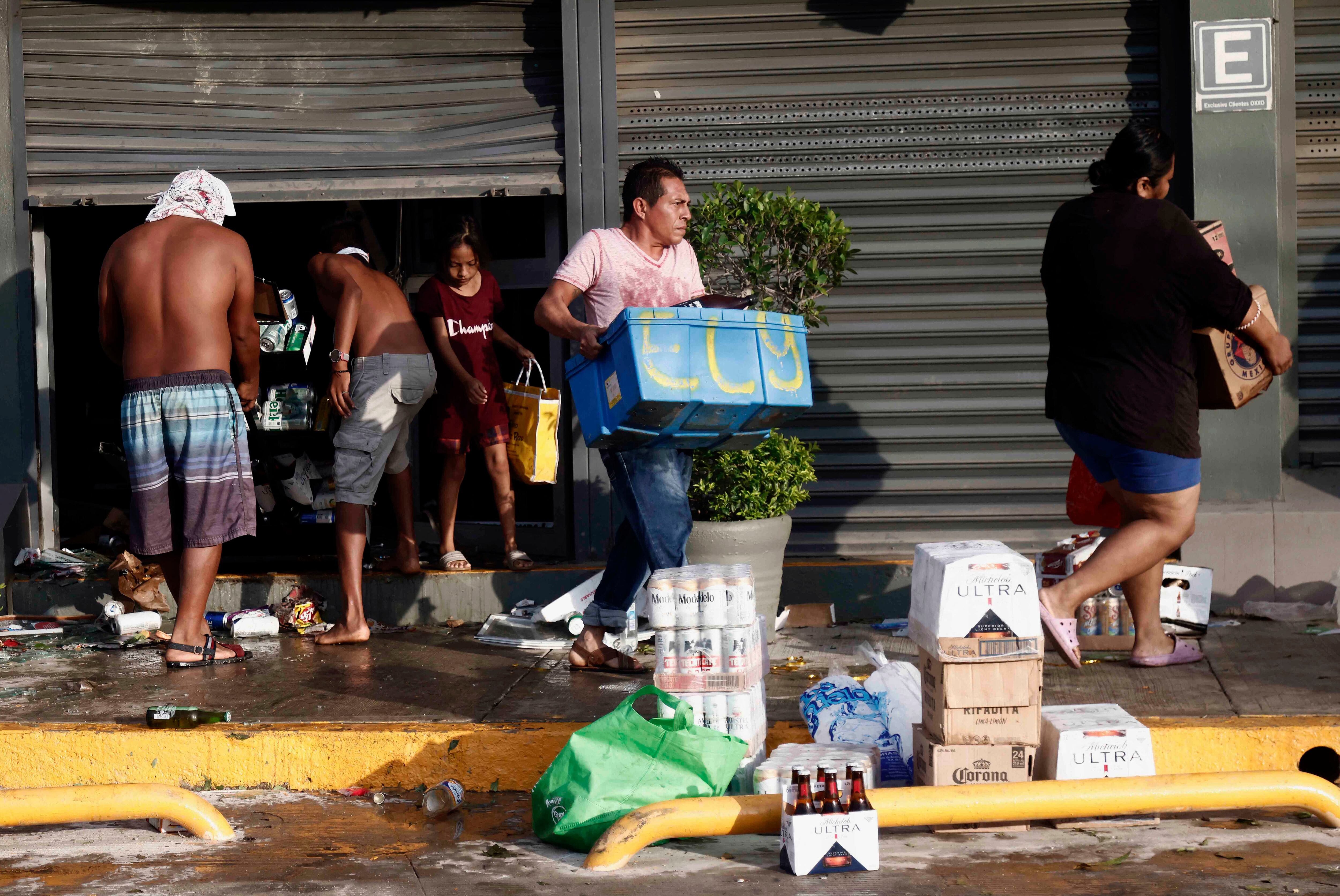 La gente recoge comestibles en un supermercado saqueado después del paso del huracán Otis en Acapulco, estado de Guerrero, México, el 26 de octubre de 2023. (Foto de RODRIGO OROPEZA/AFP).