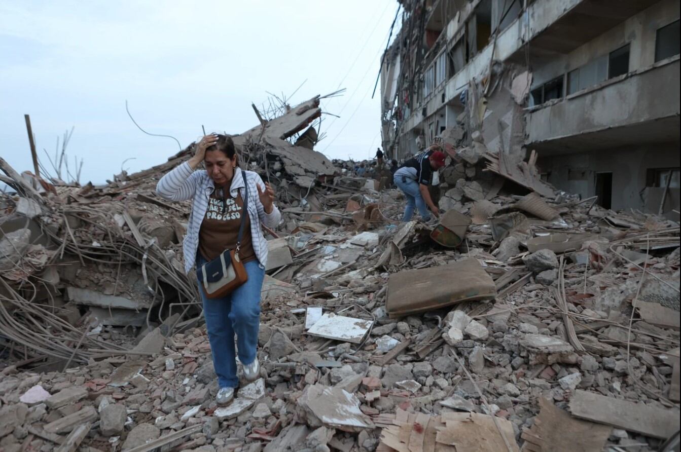 Residentes caminan entre los escombros de edificios dañados por los terremotos en Catia La Mar, Venezuela, el jueves 25 de junio de 2026. (Foto AP/Pedro Mattey).
