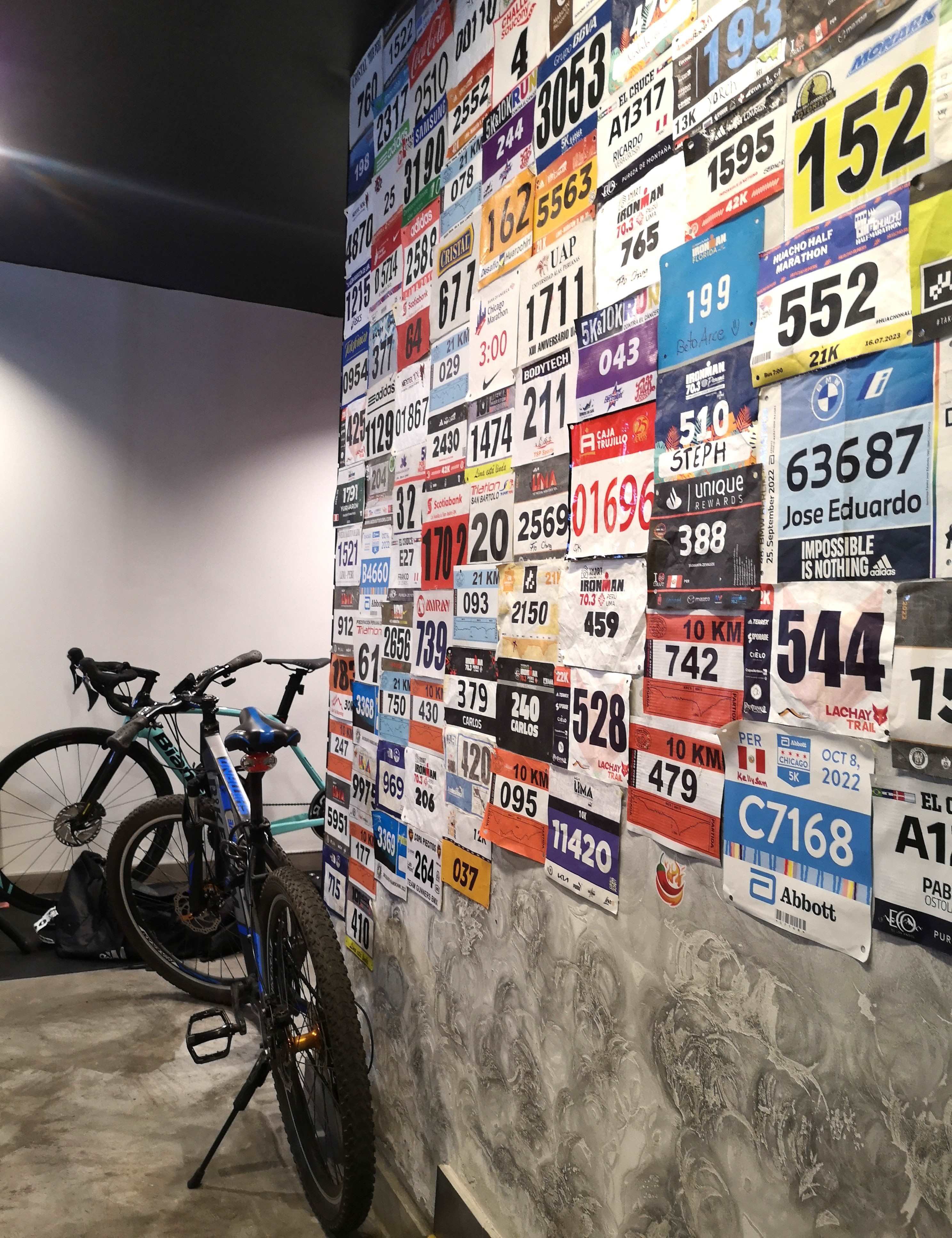 Dorsales que los clientes de Finisher Sport Café van colocando en una de las paredes interiores del local. (Foto: Norka Peralta)