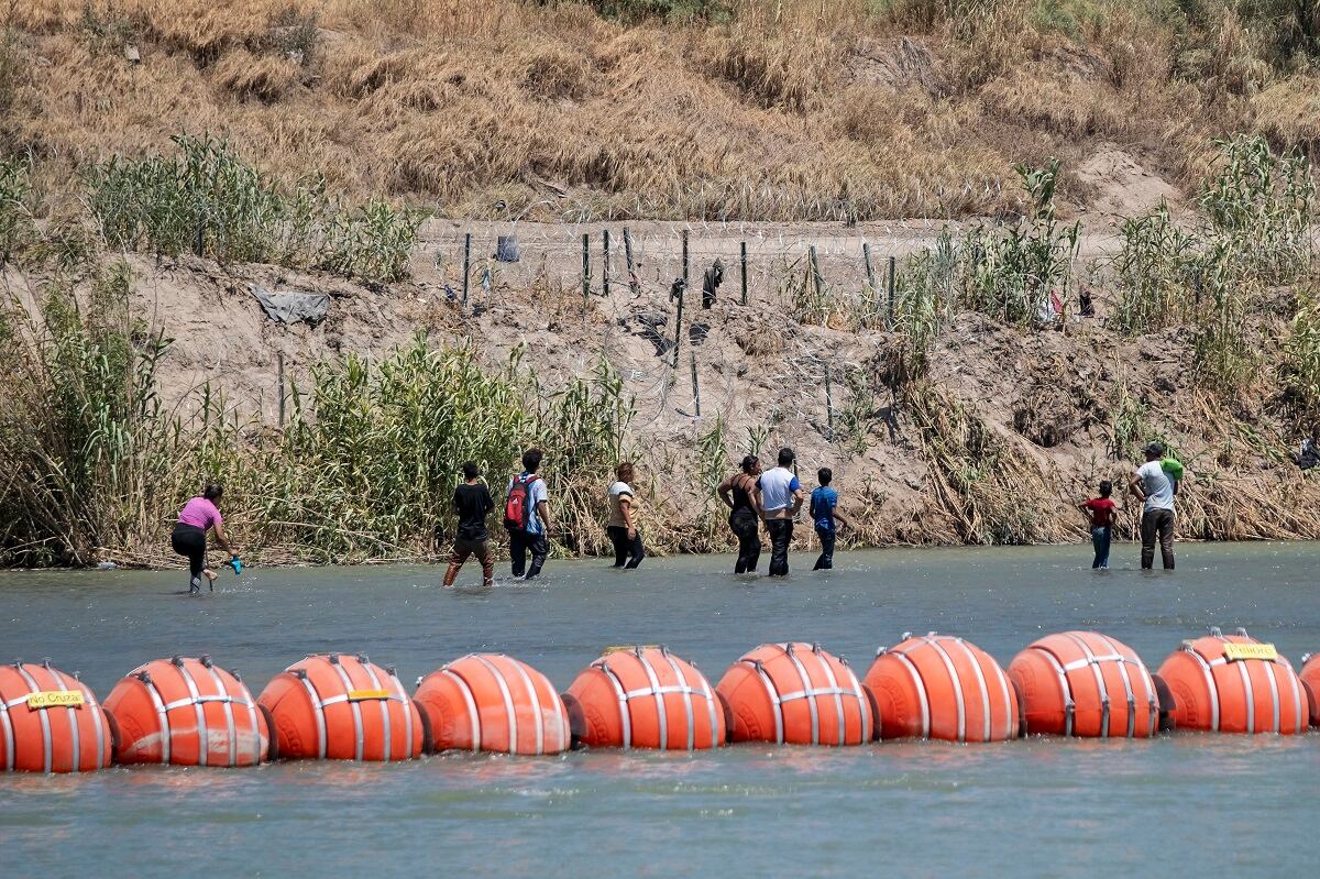 Migrantes caminan después de cruzar el río Grand hacia los Estados Unidos en Eagle Pass, Texas, visto desde Piedras Negras, estado de Coahuila, México, el 4 de agosto de 2023. (Foto de Guillermo Arias / AFP)