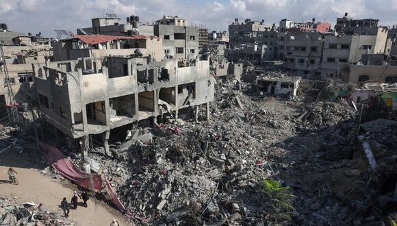 La gente pasa junto a edificios destruidos tras el bombardeo israelí de Gaza, en Bureij, en el centro de la Franja de Gaza, el 14 de noviembre de 2023, en medio de las batallas en curso entre Israel y el grupo palestino Hamás | Foto: Mohammed ABED / AFP