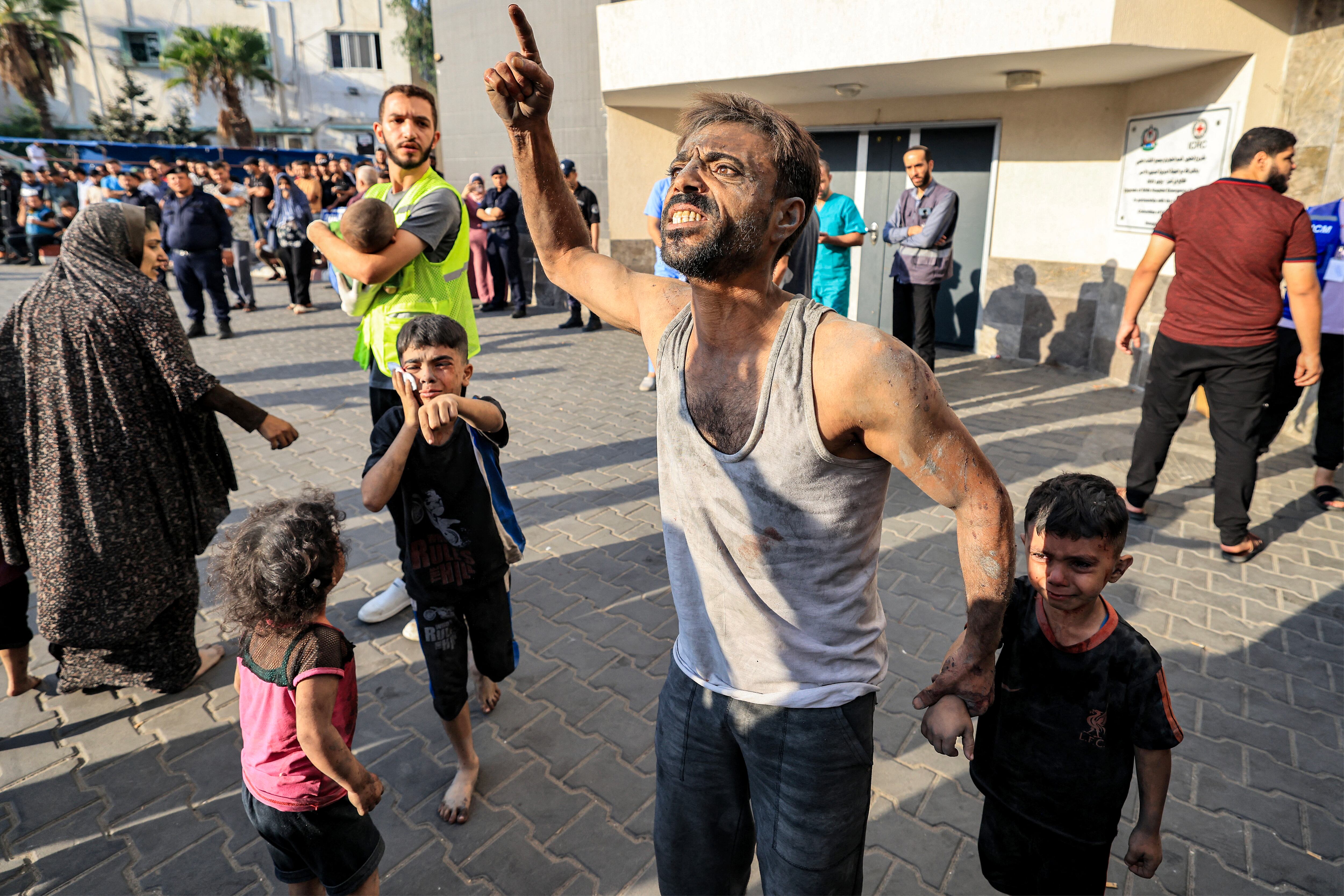 Un hombre palestino con un niño reacciona afuera del hospital al-Shifa en la ciudad de Gaza el 12 de octubre de 2023 mientras continúan los bombardeos de Israel. (Foto de Mahmud HAMS / AFP).