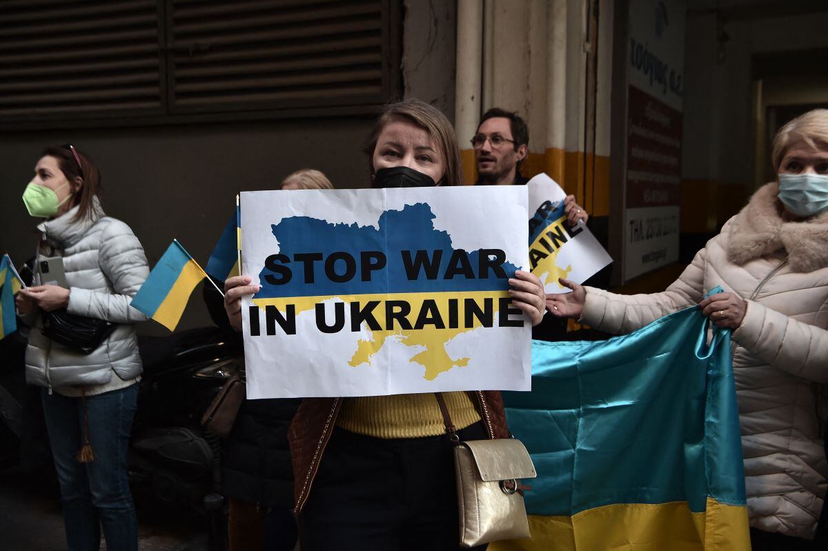 Los ucranianos que viven en Grecia sostienen banderas y pancartas nacionales durante una manifestación frente al consulado ruso en Tesalónica, luego de que Rusia lanzara un ataque contra Ucrania, el 24 de febrero de 2022 (Foto: Sakis Mitrolidis / AFP)