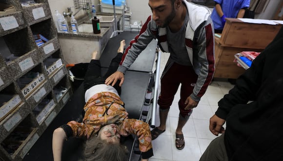 Un hombre consuela a una niña herida después de que una casa fuera alcanzada por un bombardeo de Israel en Khan Yunis, en el sur de la Franja de Gaza, el 3 de diciembre de 2023. (Foto de Mahmud HAMS / AFP).