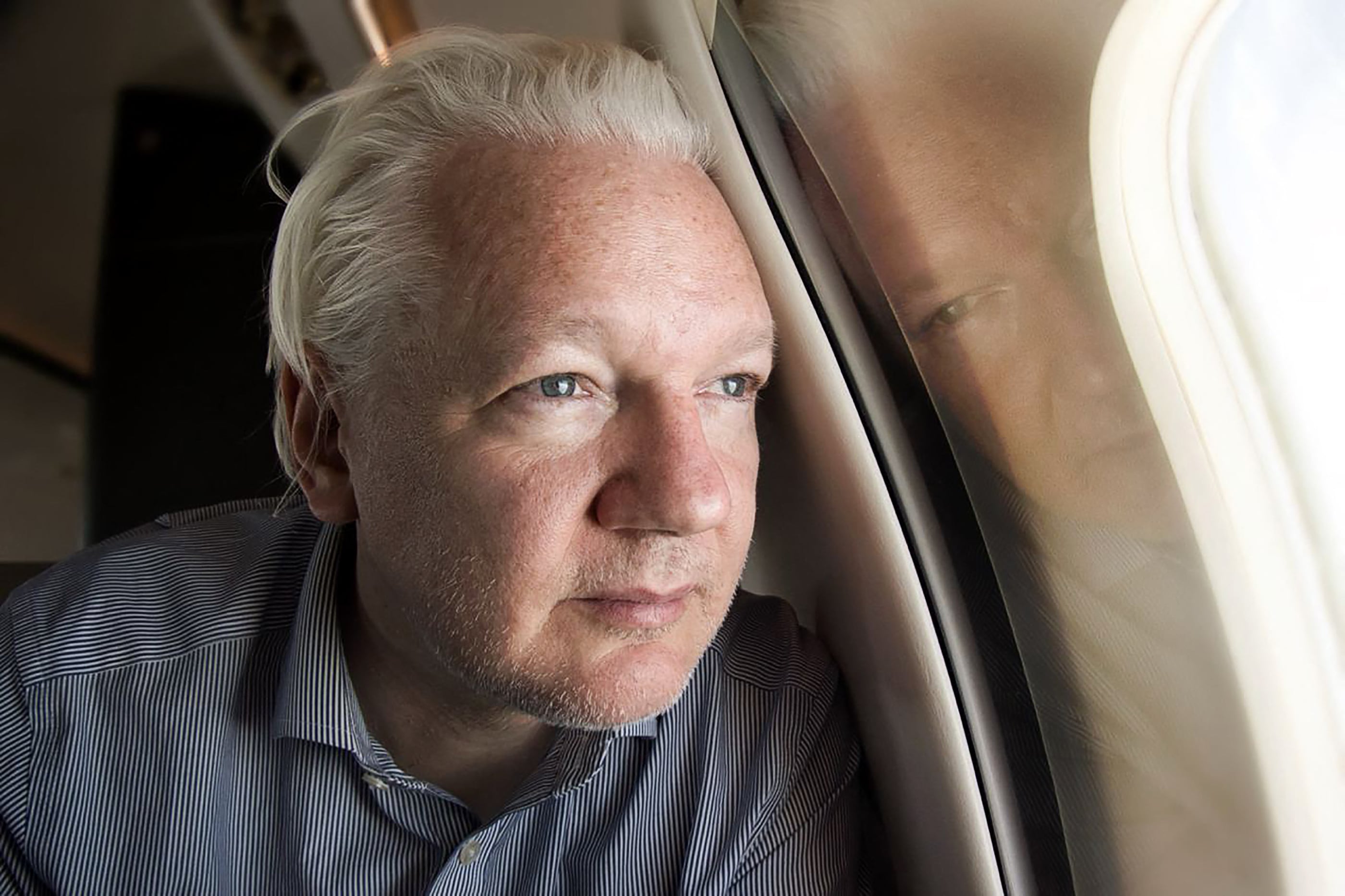 El fundador de WikiLeaks, Julian Assange, mirando por la ventana mientras su avión procedente de Londres se acerca a Bangkok para hacer una escala. (Foto de WikiLeaks / AFP).