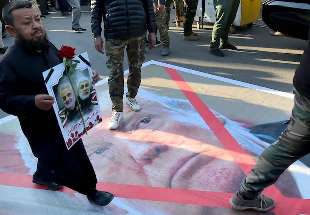 Un iraquí camina sobre un retrato de Donald Trump el 6 de enero de 2020 en Karrada, en el centro de Bagdad. (Foto de AHMAD AL-RUBAYE / AFP).