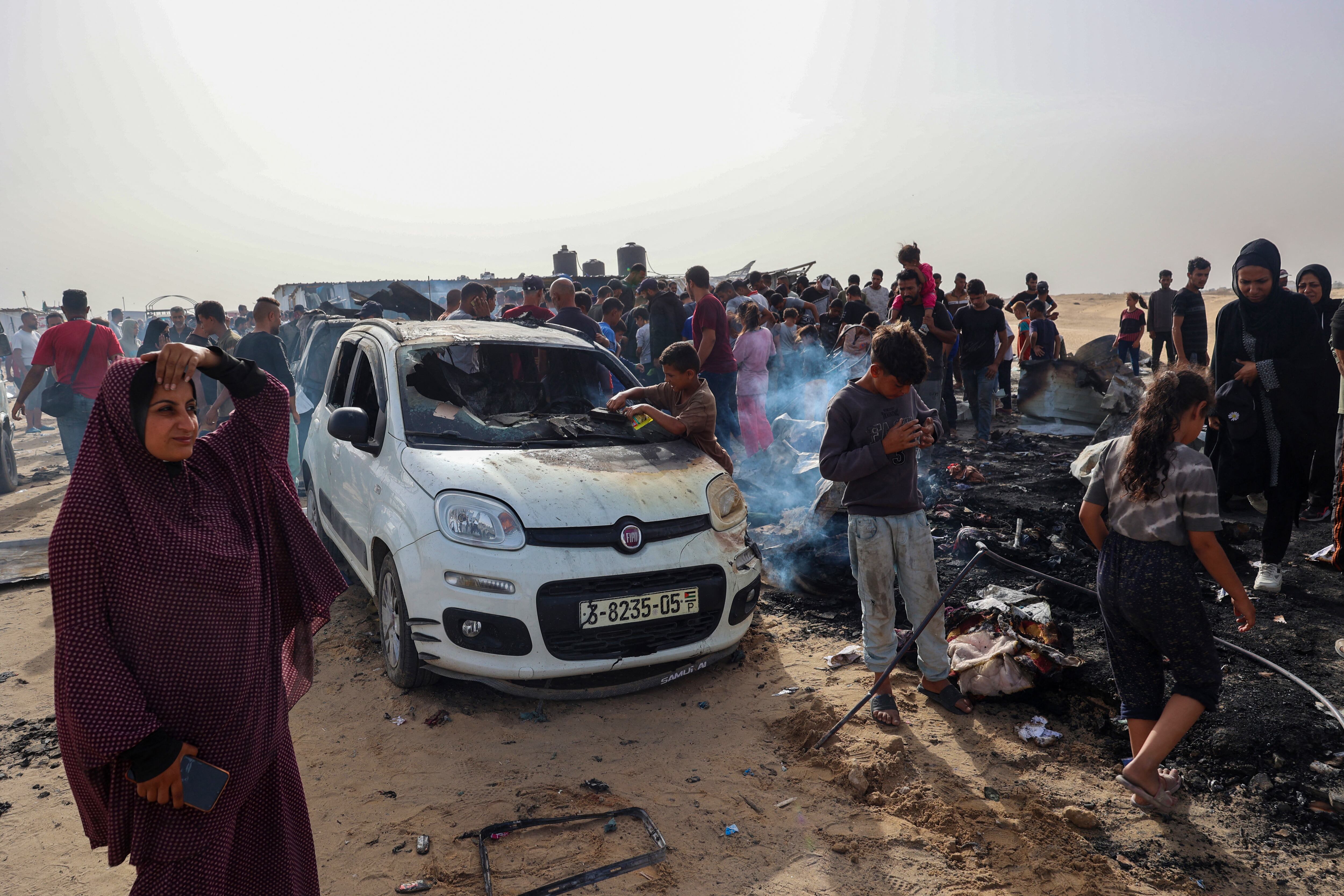 Palestinos se reúnen en el lugar de un ataque israelí en un área de campamento que alberga a desplazados internos en Rafah. (Foto de Eyad BABA / AFP)
