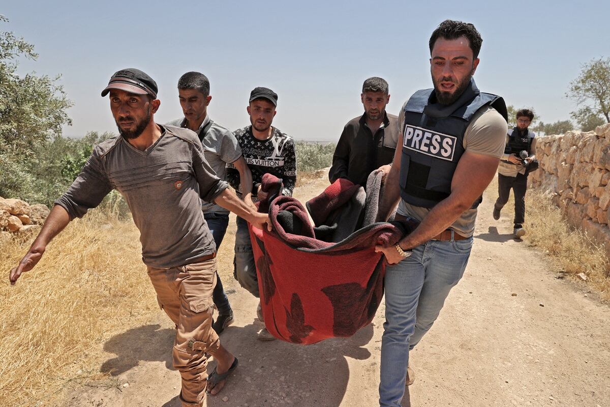 Residentes de la aldea de Serja, en la parte sur de la provincia siria de Idlib, y miembros de los medios de comunicación locales retiran el cuerpo de una niña, el 17 de julio de 2021. (Foto de OMAR HAJ KADOUR / AFP)